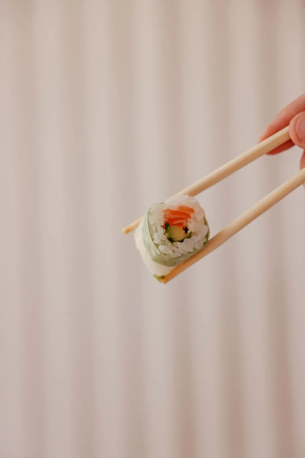 Manos sujetando palillos japoneses sobre un plato de sushi